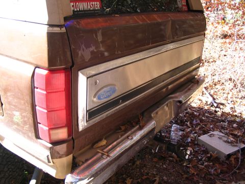 1984 Ford Bronco - The rear of a brown 1984 Ford Bronco is shown, a chrome bumper and a Flowmaster sticker on the rear window.