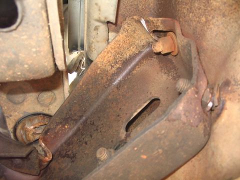 1984 Ford Bronco - Close-up view of a rusted metal bracket and bolt, likely from the undercarriage of a vehicle.