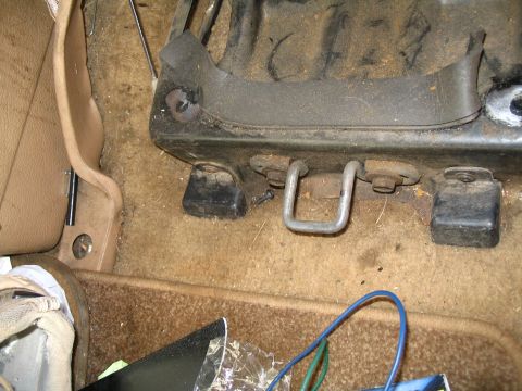 1984 Ford Bronco - Close-up of car interior floor showing seat mounting hardware and carpet.