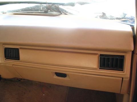 1984 Ford Bronco - The interior of a vehicle shows the dashboard area with air vents and an open glove compartment.