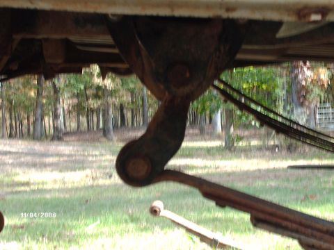 1990 Ford F-150 - A close-up view of the undercarriage reveals the leaf spring suspension system, with trees in the background.