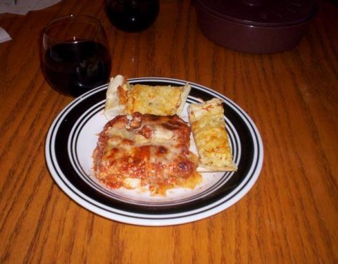 1989 Ford Bronco - A meal of lasagna and garlic bread is served with a glass of red wine on a wooden table.