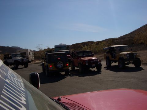 1985 Ford Bronco - A convoy of Jeeps and RVs are gathered in an outdoor setting on a sunny day.