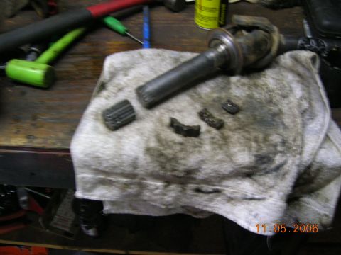 1985 Ford Bronco - Broken gear teeth and a driveshaft lie on a stained towel, with tools visible on a wooden workbench.