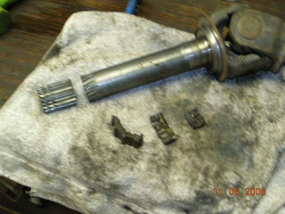 Broken driveshaft with splines sheared off and pieces on a rag