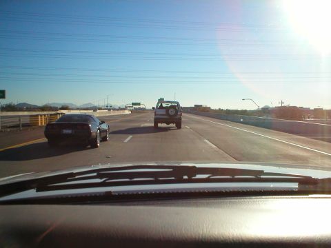 1993 Ford Bronco - A white SUV is seen from behind on a highway, with a spare tire mounted on its rear door.