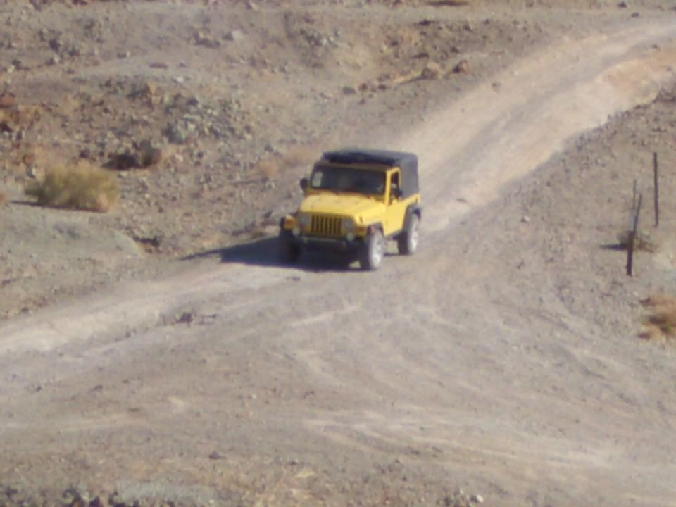 Yellow Jeep Wrangler on a dirt road