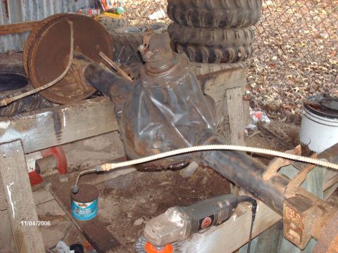 1990 Ford F-150 - Front axle assembly, likely for a truck, shown outdoors with tools and spare tires.