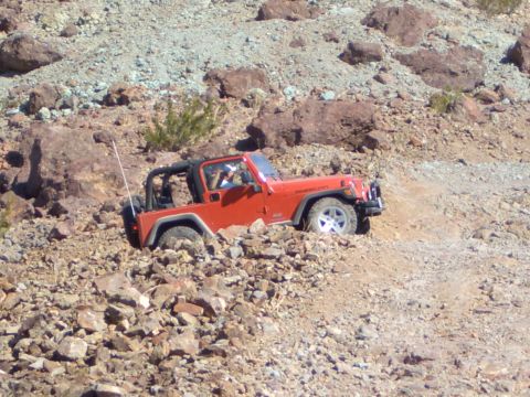 1985 Ford Bronco - A Jeep Wrangler Rubicon is shown navigating a challenging, rocky off-road trail.