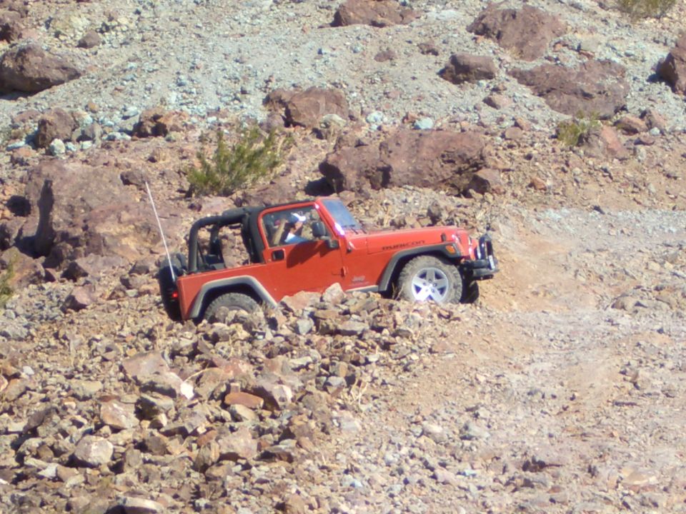 Orange Jeep Wrangler Rubicon navigating rocky terrain
