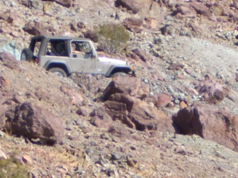 1985 Ford Bronco - A tan Jeep Wrangler TJ navigates a steep, rocky terrain.