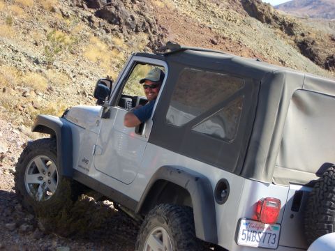 1985 Ford Bronco - Driver navigates a silver Jeep Wrangler Rubicon through a challenging off-road terrain.