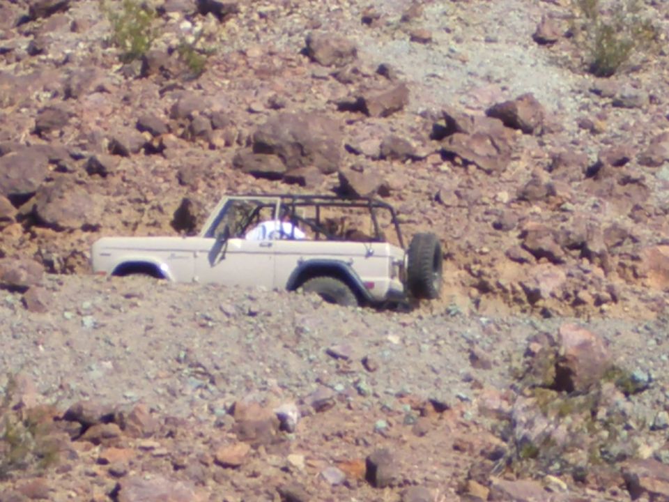 Tan Ford Bronco stuck in rocky terrain, side view
