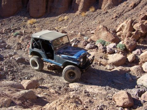1985 Ford Bronco - A modified Jeep CJ-7 navigates a challenging rocky terrain, its off-road capabilities.