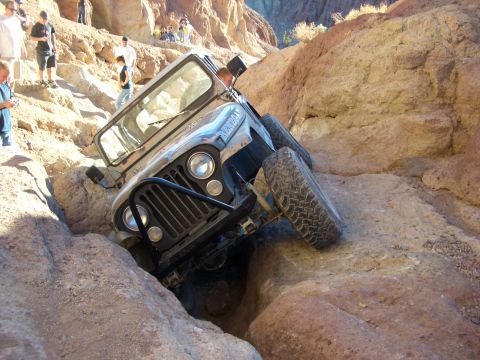 1985 Ford Bronco - A Jeep CJ-7 is shown navigating a challenging rocky terrain in a canyon.