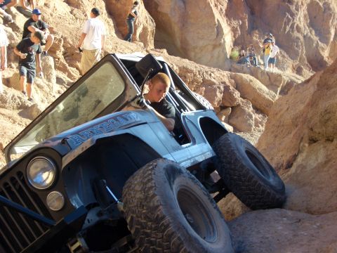1985 Ford Bronco - A Jeep CJ-7 Renegade navigates a challenging rocky terrain with onlookers observing from above.