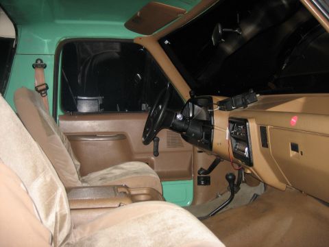 1990 Ford Bronco - The interior of the vehicle shows tan seats and a brown dashboard with some aftermarket accessories attached.