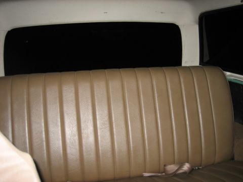 1990 Ford Bronco - The rear bench seat of a vehicle is shown, tan vinyl upholstery and a dark rear window.