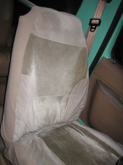 1990 Ford Bronco - Interior view of a car seat covered in tan fabric, with a beige seatbelt attached to the right.