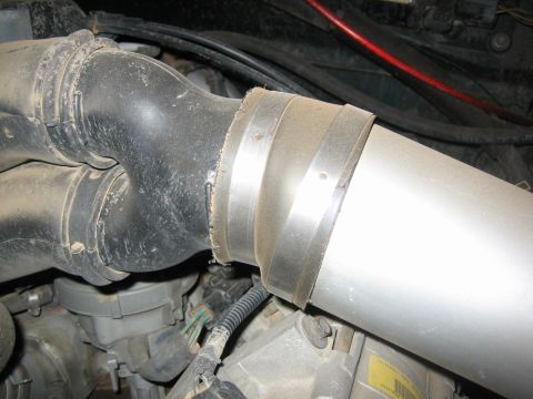 1995 Ford Bronco - The intake tube and associated engine components are covered in a layer of dust.