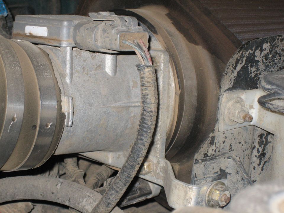 Close-up of a mass air flow sensor with wiring harness attached to an intake tube