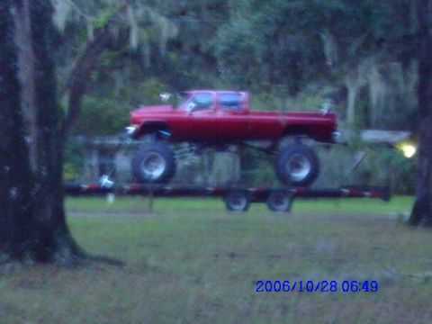 1987 Suzuki Samurai - A red pickup truck is elevated on a trailer, with trees in the background and a timestamp of 2006/10/28.
