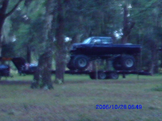 Black pickup truck with large tires on a trailer, side view