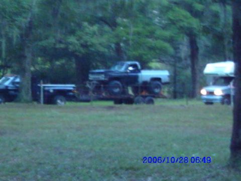 1987 Suzuki Samurai - A two-tone truck is loaded onto a trailer, with other vehicles and a camper visible in the background.