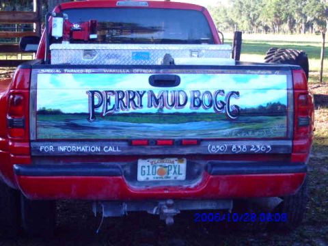 1987 Suzuki Samurai - Rear view of a red pickup truck a custom mural on the tailgate with contact information.