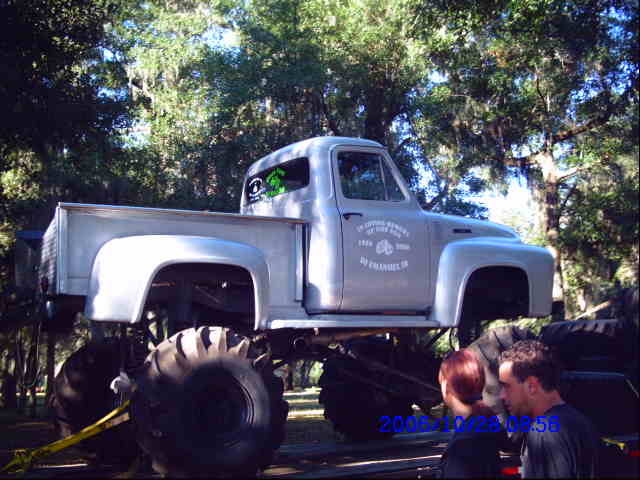 Gray monster truck with large tires, lifted suspension, and custom decals on the door