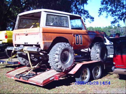 1987 Suzuki Samurai - Ford Bronco with oversized tires being transported on a trailer.