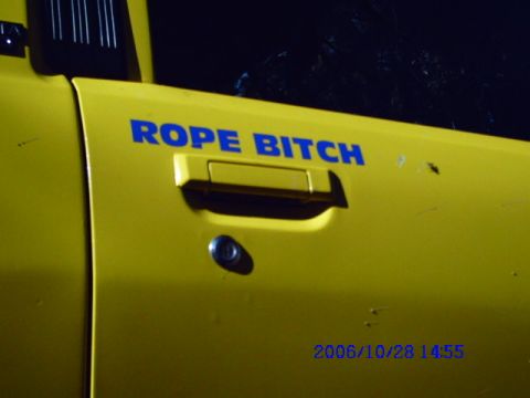1987 Suzuki Samurai - A yellow vehicle door displays the text "ROPE BITCH" above the door handle.