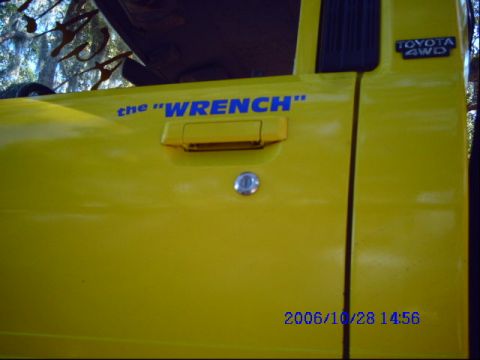 1987 Suzuki Samurai - Close-up of a yellow vehicle door, showing a custom text decal and a Toyota 4WD badge.