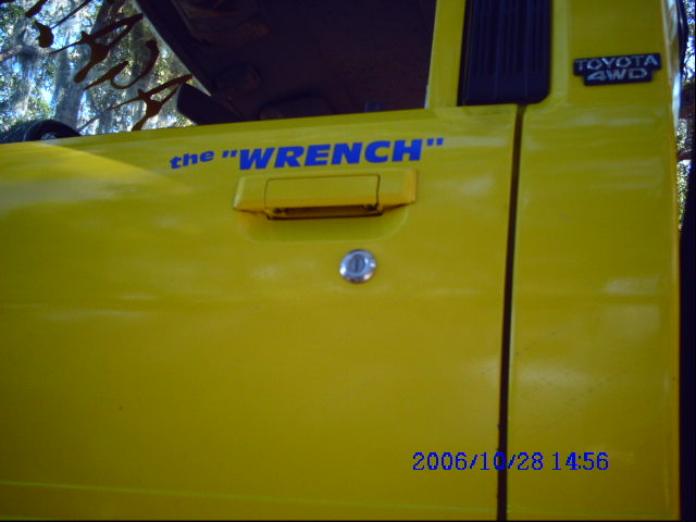 Yellow vehicle door with blue text "the \"WRENCH\"" and a "TOYOTA 4WD" badge