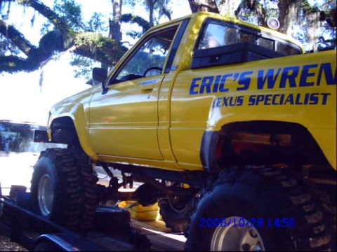 1987 Suzuki Samurai - A yellow pickup truck with large off-road tires is seen on a trailer, with text indicating it is a Lexus specialist.