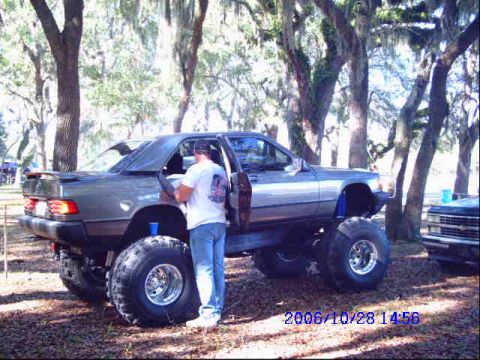 1987 Suzuki Samurai - A heavily modified Mercedes-Benz sedan sits on oversized tires, with another vehicle nearby.