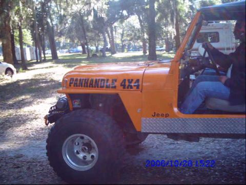 1987 Suzuki Samurai - Side view of an orange Jeep CJ with off-road tires and a roll cage visible.