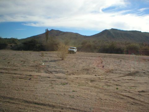 1993 Ford Bronco - White SUV driving through a desert landscape with mountains in the distance.