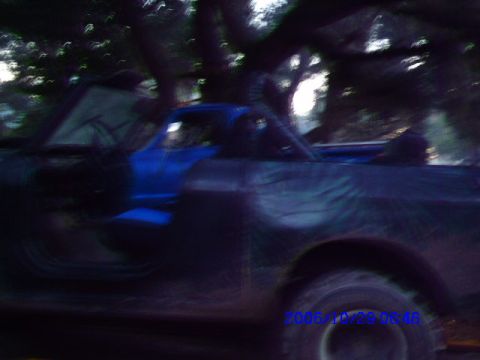 1987 Suzuki Samurai - A blurry side view captures a blue and black pickup truck, possibly modified, with a soft top.