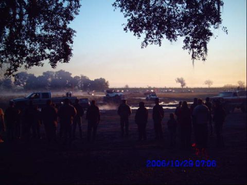 1987 Suzuki Samurai - A group of people watch vehicles in the distance during a foggy sunrise.