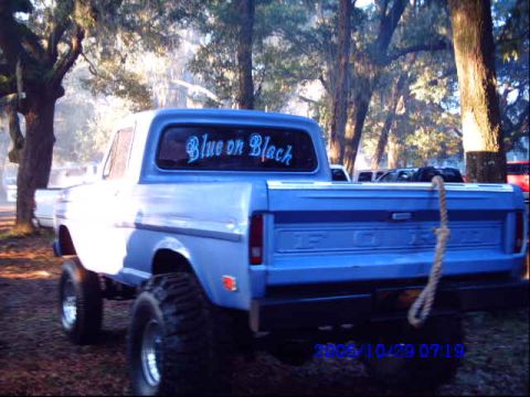 1987 Suzuki Samurai - A blue pickup truck is seen from the rear, with custom text on the back window.