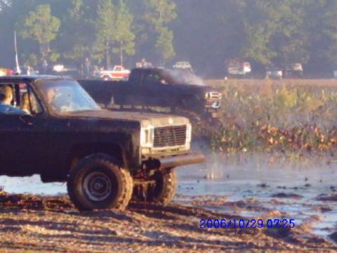 1987 Suzuki Samurai - Multiple trucks are seen in a muddy field, with one in the foreground.
