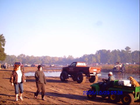 1987 Suzuki Samurai - A muddy field hosts a mud bogging event with several lifted trucks and people enjoying the outdoors, captured on October 29, 2006.