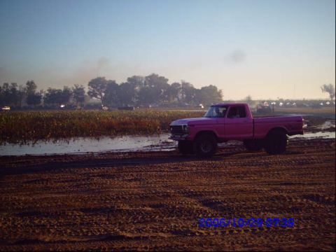 1987 Suzuki Samurai - Pink pickup truck in a muddy field during sunrise.