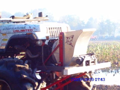1987 Suzuki Samurai - A modified Jeep with a large spreader attachment is seen in a field with other vehicles in the background.