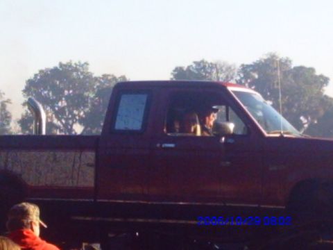 1987 Suzuki Samurai - A red pickup truck with a lifted suspension and a prominent side exhaust pipe is visible.