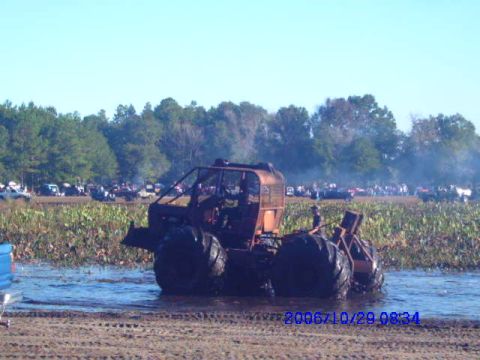 1987 Suzuki Samurai - A custom-built mud bogger navigates through a muddy field with spectators watching in the distance.