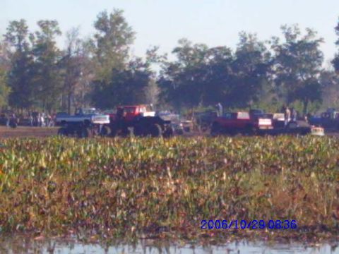 1987 Suzuki Samurai - Multiple trucks are visible at a mud bog event, with spectators in the background.
