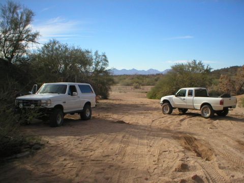1993 Ford Bronco - A white 1993 Ford Bronco and a white Ford Ranger sit in a desert landscape under a clear blue sky.