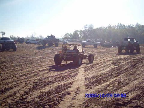1987 Suzuki Samurai - Multiple off-road vehicles are gathered in a sandy area, with tire tracks visible on the ground.
